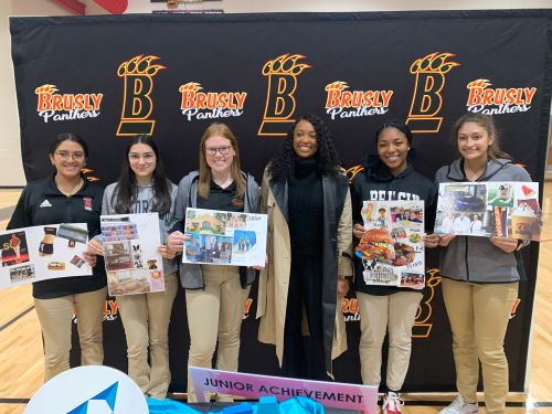 Female Mentor posing with 5 students against backdrop